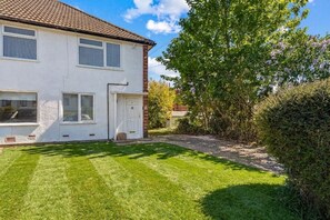 Una casa de dos pisos con un césped cuidado y un árbol grande en el patio.