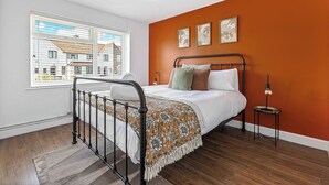 A bedroom with a bed, a window, a radiator, and a small table with a lamp. - Modern 2-Bed Apartment in Reading (Berkshire)