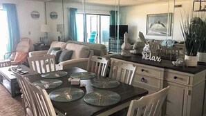 Ein Wohnzimmer mit Esstisch, Stühlen, einer Couch und einer Küchenzeile mit Arbeitsplatte.