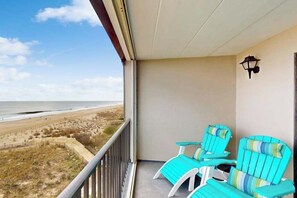 A balcony with two turquoise chairs, a small table, and a wall-mounted lamp. - Ocean Trail 503 (Ocean City)