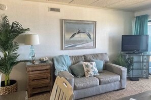A living room with a sofa, a television, a framed picture, and a lamp. - Ocean Trail 503 (Ocean City)