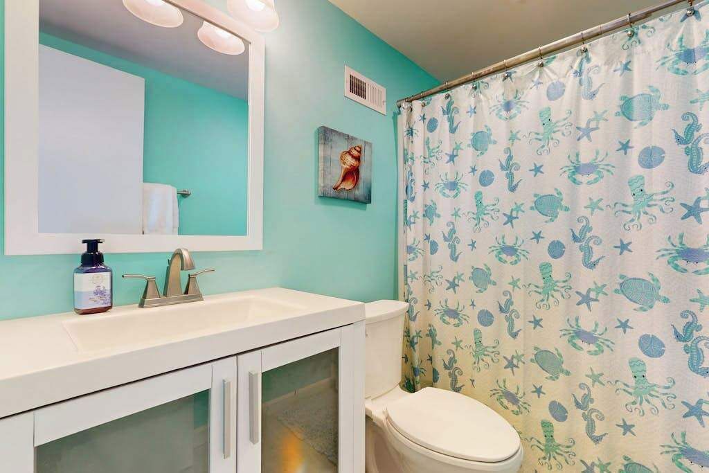 A bathroom with a toilet, sink, and mirror.