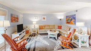 Ein Wohnzimmer mit einer Couch, Sesseln, einem Couchtisch und Kunstwerken an den Wänden.