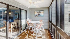 Ein Balkon mit Tisch und Stühlen, einem Deckenventilator und einem Bild an der Wand.