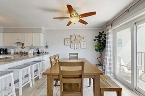 A dining area with a wooden table, chairs, a ceiling fan, and a large window with a view. - Second-Floor Condo 1 Block from the Beach w/ Balcony, AC, WiFi & Shared Pool (Ocean City)