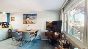 Una sala de estar con una mesa de comedor, sillas, un televisor y obras de arte en las paredes.