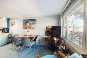 A living room with a dining table, chairs, a television, and artwork on the walls. - Old Wharf 8 (Ocean City)