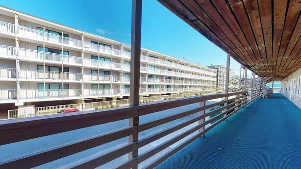 Un hotel de varios pisos con balcones, un paseo cubierto y vistas al agua.