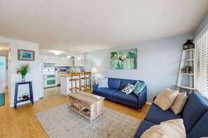 A living room with a sofa, coffee table, and a painting on the wall. - Budget-Friendly Beach Condo w/Private Washer/Dryer, Central A/C, WiFi (Ocean City)
