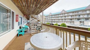 Ein Balkon mit Holzboden, einem runden Tisch und türkisfarbenen Stühlen.