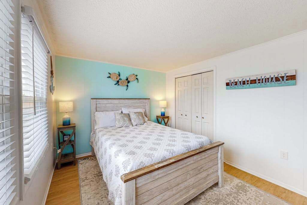 Une chambre à coucher avec un lit, des lampes de chevet, un élément de décoration murale, une porte et un panneau affiché sur le mur.