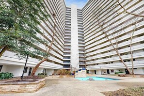 A multi-story residential building with a central courtyard and a swimming pool. - Modern, ocean-view condo with balcony, pools, saunas, tennis & gym (Ocean City)
