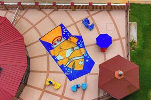 A patio with a geometric tile pattern, outdoor seating, and umbrellas. - Beachfront condo with balcony, game room, pools, sauna & gym (Ocean City)