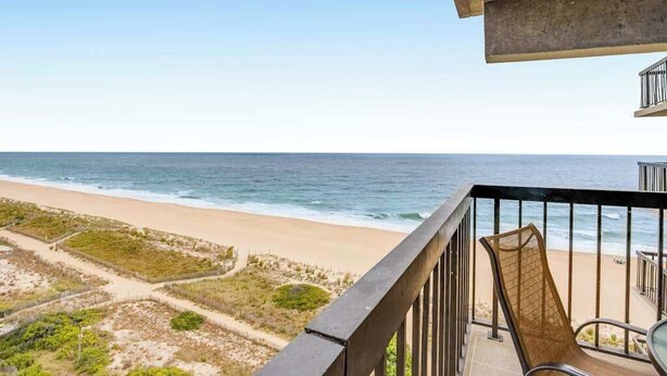 A balcony with a view of the beach and ocean. - Beachfront corner condo with balcony, pools, sauna & tennis (Ocean City)