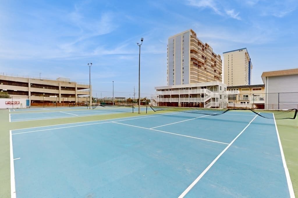 A multi-level parking structure, a tennis court, and a building with balconies.