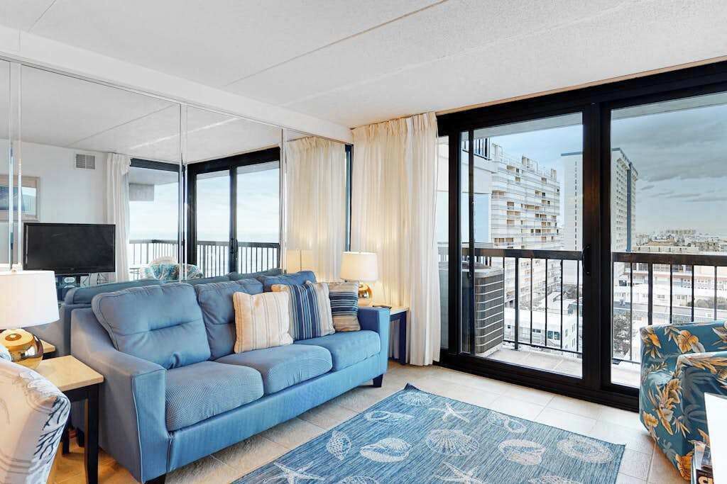 Un salon moderne avec un canapé, un téléviseur et un balcon offrant une vue sur la ville.
