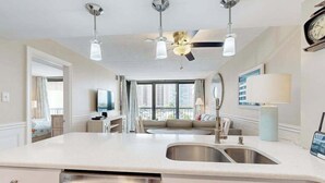 A modern kitchen with a central island, stainless steel appliances, and a ceiling fan. - Stylish inviting beach condo with balcony, pools, gym & sauna (Ocean City)