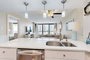 A modern kitchen with a central island, stainless steel appliances, and a ceiling fan. - Stylish inviting beach condo with balcony, pools, gym & sauna (Ocean City)