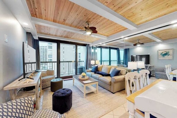 A modern living room with a sofa, coffee table, and dining area. - Spacious beach condo with balcony, beach views, pools, gym & AC (Ocean City)