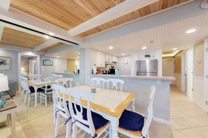 A modern kitchen with white cabinets, a stainless steel refrigerator, and a wooden ceiling. - Spacious beach condo with balcony, beach views, pools, gym & AC (Ocean City)