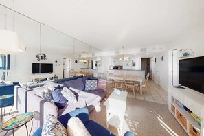 A modern living space with a sofa, dining area, and kitchen. - Fabulous beach condo with AC, pools, sauna, gym, game room & tennis (Ocean City)