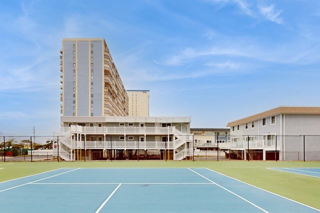 Ein mehrstöckiges Gebäude mit einem Tennisplatz davor.