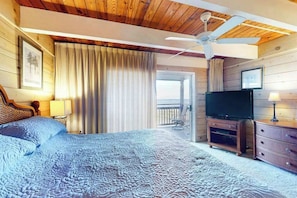 Een slaapkamer met een groot bed, een plafondventilator, een televisie en een balkon.