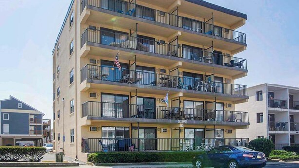 A multi-story apartment building with balconies, windows, and a flag.