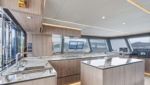 A modern kitchen with a central island, built-in appliances, and large windows offering views of the outside.