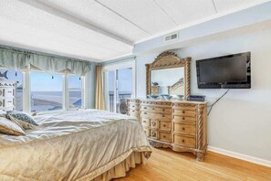 Ein Schlafzimmer mit einem großen Bett, einem Schminktisch, einem Fernseher und einem Fenster mit Blick.