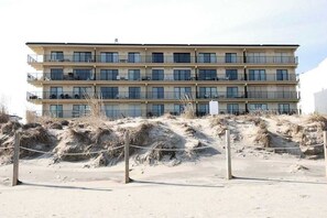 A multi-story hotel with balconies, located near a sandy beach area. - Oceanfront, Ground-Floor Condo w/ Patio, Fast WiFi, Central AC & Washer/Dryer (Ocean City)