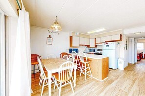 Een keuken met een eethoek, houten vloeren en witte kastjes.