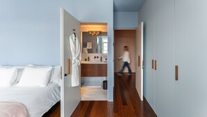 Ein Schlafzimmer mit Bett, Bademantel und einem Badezimmer mit Waschbecken und Spiegel.