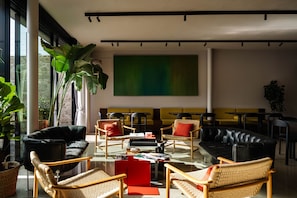 A modern lounge area with leather sofas, wicker chairs, and a large abstract painting on the wall. - Porto Arts Club Apartment II by Feel Discovery (Porto)