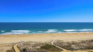 A beach with a clear sky, sandy shore, and a fenced dune area. - Oceanfront condo with ocean view, private W/D, central AC, and pool access (Ocean City)