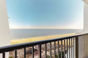 A balcony with a view of the beach and ocean. - Oceanfront Condo with a Shaded Balcony, AC, WiFi & Shared Outdoor Pool (Ocean City)