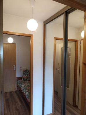 Um quarto com uma cama, uma porta de madeira, um espelho e um lustre.