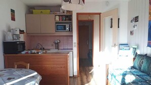 A compact living space with a kitchenette, a dining area, and a bedroom.