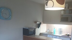 A compact kitchen with a microwave, toaster, sink, and a small dining area with a table and chairs.