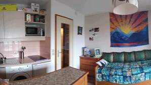 A small room with a bed, a table, a microwave, and a sink.