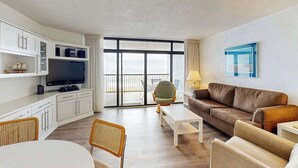 Una sala de estar moderna con un televisor de pantalla plana, un sofá, una mesa de centro y un comedor.