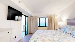 A hotel room with a bed, a TV, a window with curtains, and a view of the sea. - Plaza 1109 (Ocean City)