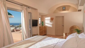 Ein Schlafzimmer mit einem Bett, einem Fernseher, einem Holzschrank und Blick aufs Meer.