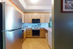 Eine kleine Küche mit Kühlschrank, Mikrowelle, Herd und Schränken.