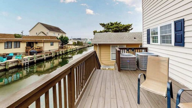 Une terrasse en bois avec des sièges extérieurs, un cours d’eau et une maison dotée d’un quai.