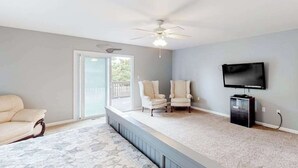Une pièce dotée d’un ventilateur de plafond, d’une télévision, de deux fauteuils, d’un canapé et d’un tapis à motifs.