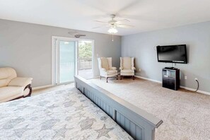 A room with a ceiling fan, a television, two chairs, a sofa, and a patterned rug. - Multi-Level Home Close to the Beach w/Air Hockey, Free WiFi, Decks, & Balconies (Ocean City)