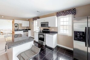 A modern kitchen with white cabinets, a stainless steel refrigerator, a microwave, and a coffee maker. - Multi-Level Home Close to the Beach w/Air Hockey, Free WiFi, Decks, & Balconies (Ocean City)