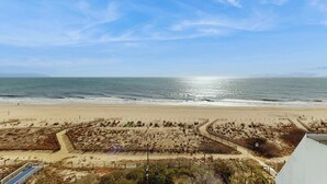 Blick auf einen Strand mit sandigem Ufer, blauem Himmel und ruhiger See.
