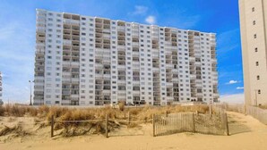 Ein mehrstöckiges Hotel mit einheitlicher Fassade in Strandnähe, mit einer Holzlattenumzäunung.